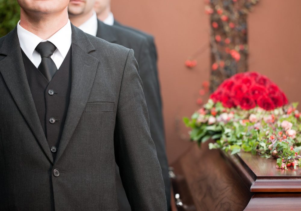 Religion, death and dolor  - coffin bearer carrying casket at funeral to cemetery