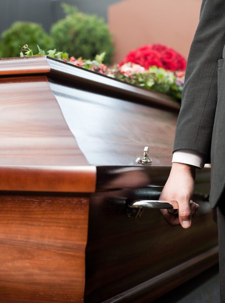 Religion, death and dolor  - coffin bearer carrying casket at funeral to cemetery